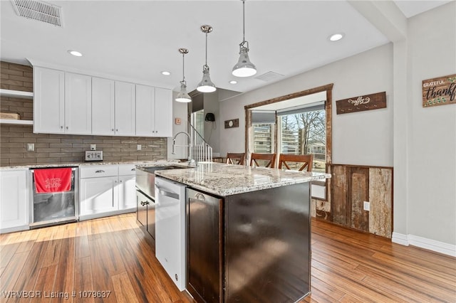 kitchen with visible vents, light wood finished floors, white cabinets, pendant lighting, and tasteful backsplash