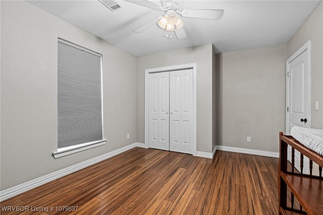 unfurnished bedroom featuring visible vents, baseboards, wood finished floors, a closet, and a ceiling fan