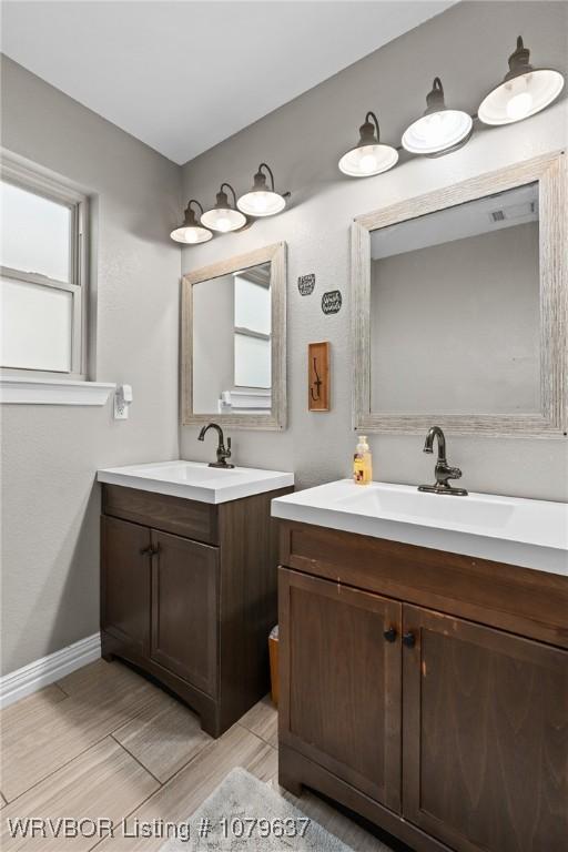 bathroom with two vanities, baseboards, and a sink