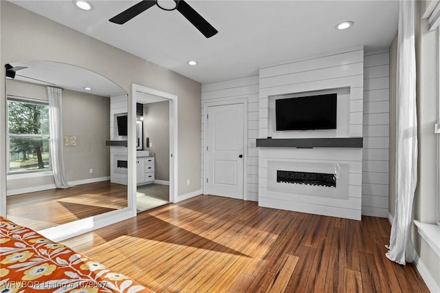 unfurnished living room with ceiling fan, recessed lighting, wood finished floors, and a large fireplace