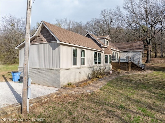 view of property exterior featuring stairway, a lawn, brick siding, and roof with shingles