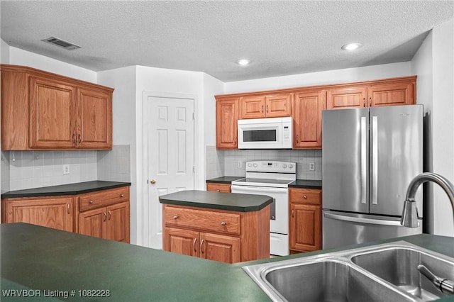 1121 Bourland St, Arkoma, OK 74901 - kitchen with white appliances, dark countertops, backsplash, brown cabinets, and a textured ceiling