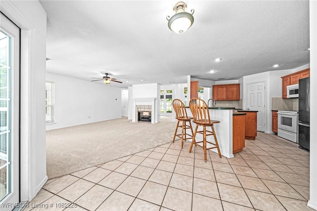 1121 Bourland St, Arkoma, OK 74901 - kitchen featuring stove, white microwave, a breakfast bar, light carpet, and fridge