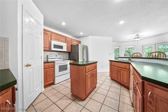 1121 Bourland St, Arkoma, OK 74901 - kitchen with white appliances, dark countertops, a kitchen island, tasteful backsplash, and a textured ceiling