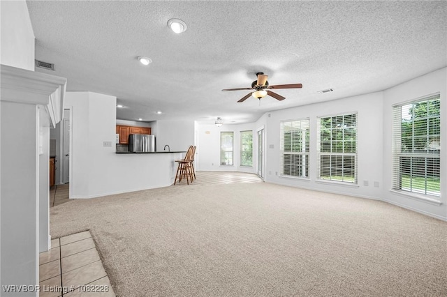 1121 Bourland St, Arkoma, OK 74901 - unfurnished living room with light colored carpet, ceiling fan, plenty of natural light, a textured ceiling, and recessed lighting
