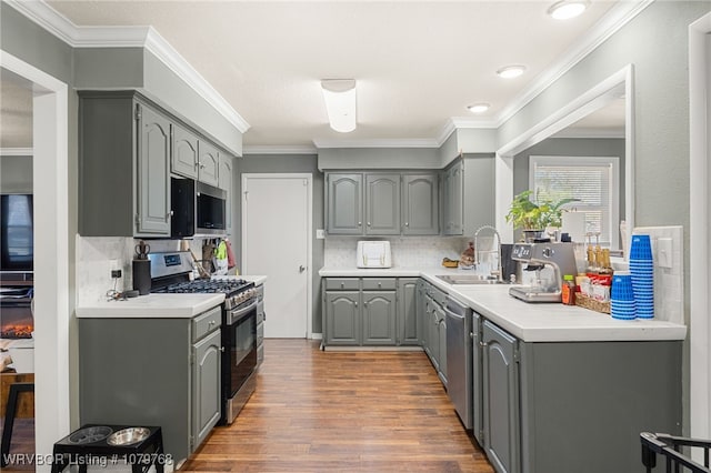 8005 Holly Ave, Fort Smith, AR 72908 - kitchen with wood finished floors, a sink, gray cabinetry, light countertops, and appliances with stainless steel finishes