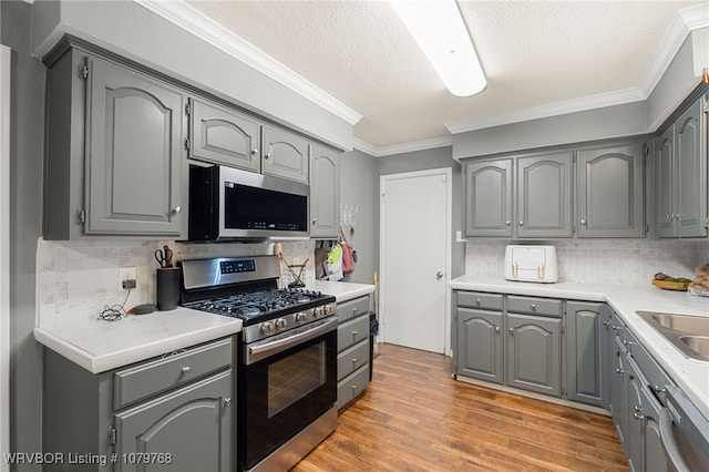 8005 Holly Ave, Fort Smith, AR 72908 - kitchen with light wood-style flooring, gray cabinets, ornamental molding, stainless steel appliances, and light countertops