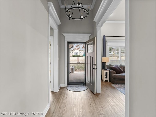 entryway featuring hardwood / wood-style flooring, ornamental molding, and a notable chandelier