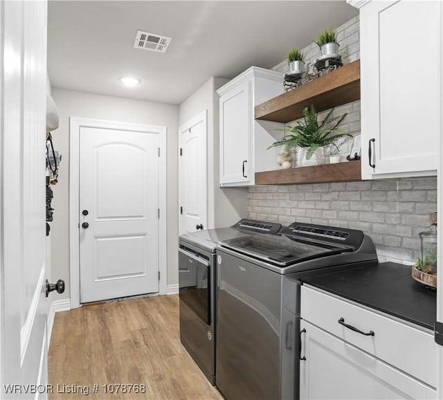 washroom with cabinets, washing machine and clothes dryer, and light hardwood / wood-style floors