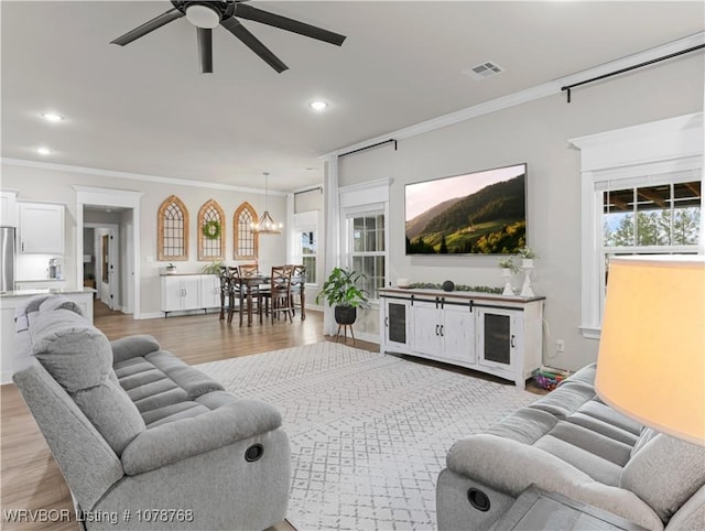 living room with crown molding, light hardwood / wood-style flooring, and ceiling fan with notable chandelier