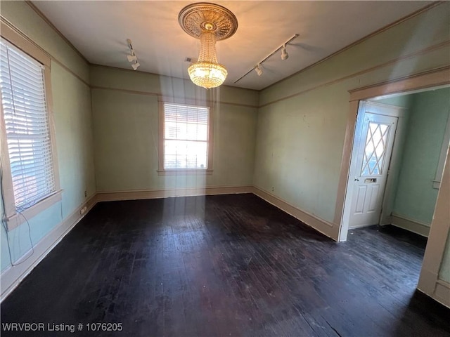 empty room with rail lighting and dark hardwood / wood-style floors