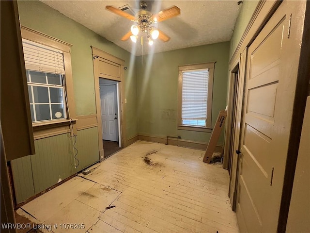 interior space with ceiling fan, a textured ceiling, and light hardwood / wood-style flooring