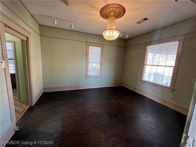 empty room with dark hardwood / wood-style flooring and an inviting chandelier