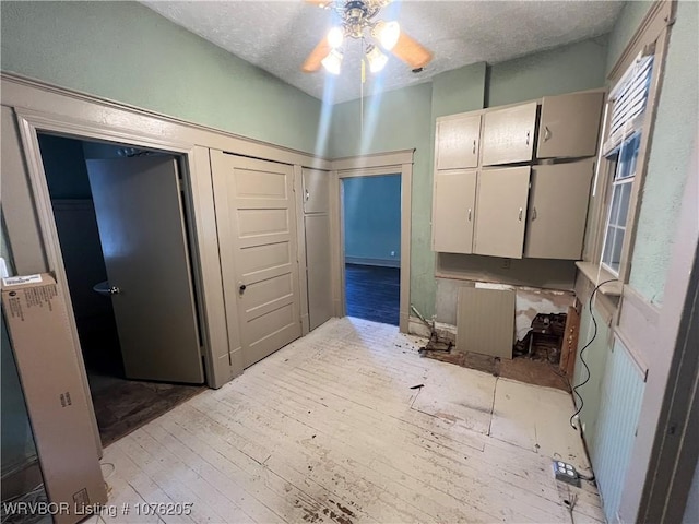 bathroom with ceiling fan, wood-type flooring, and a textured ceiling