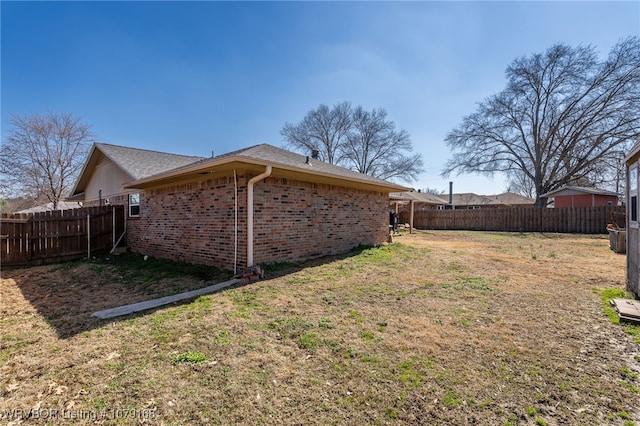 exterior space featuring fence, a lawn, and brick siding