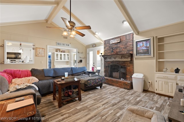 living area with visible vents, lofted ceiling with beams, light wood-style flooring, ceiling fan, and a fireplace