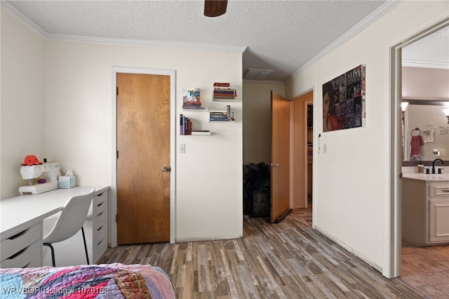 bedroom featuring light wood finished floors, ornamental molding, and a textured ceiling