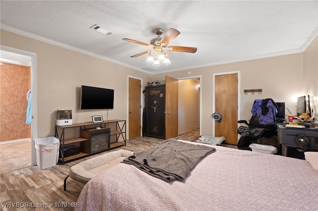 bedroom featuring light wood finished floors, visible vents, and crown molding