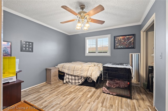 bedroom featuring a textured ceiling, wood finished floors, a ceiling fan, baseboards, and ornamental molding