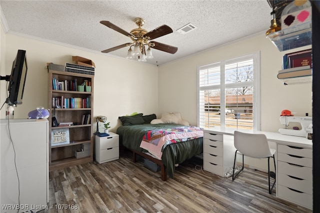 bedroom with a textured ceiling, wood finished floors, visible vents, and crown molding