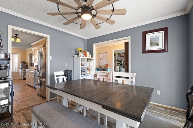 dining room with a textured ceiling, wood finished floors, a ceiling fan, baseboards, and crown molding