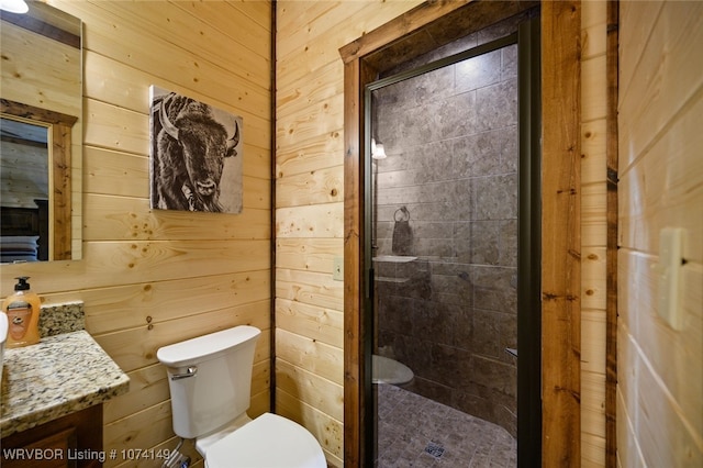 bathroom with vanity, toilet, a shower with door, and wooden walls