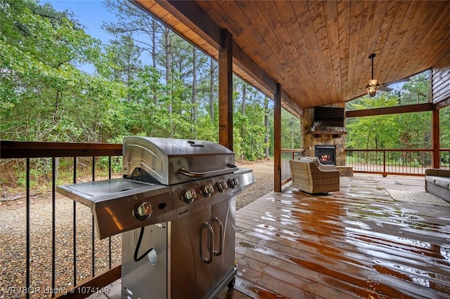 wooden deck featuring an outdoor stone fireplace and a grill