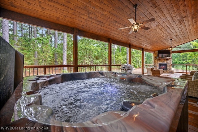 deck with an outdoor stone fireplace, grilling area, a hot tub, and ceiling fan