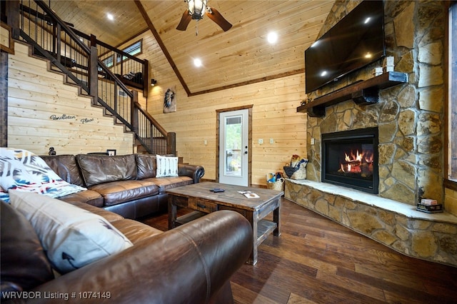 living room with hardwood / wood-style floors, wood walls, a stone fireplace, ceiling fan, and wood ceiling