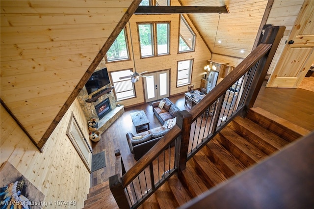 stairs featuring wooden ceiling, high vaulted ceiling, wood-type flooring, a fireplace, and ceiling fan with notable chandelier