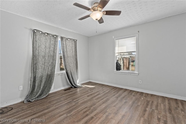 unfurnished room featuring a textured ceiling, wood finished floors, a ceiling fan, and baseboards