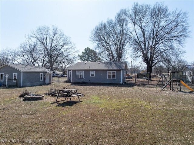 back of property featuring a fire pit and a playground