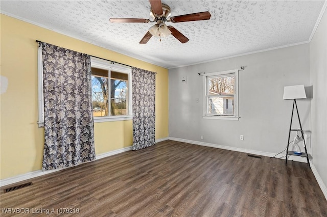 spare room with a textured ceiling, wood finished floors, and visible vents