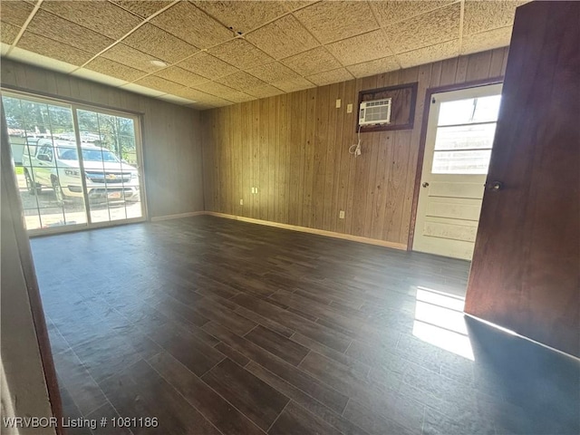 1117 W Creek Ave, Sallisaw, OK 74955 - unfurnished room featuring baseboards, a wall mounted air conditioner, dark wood-style flooring, and wooden walls
