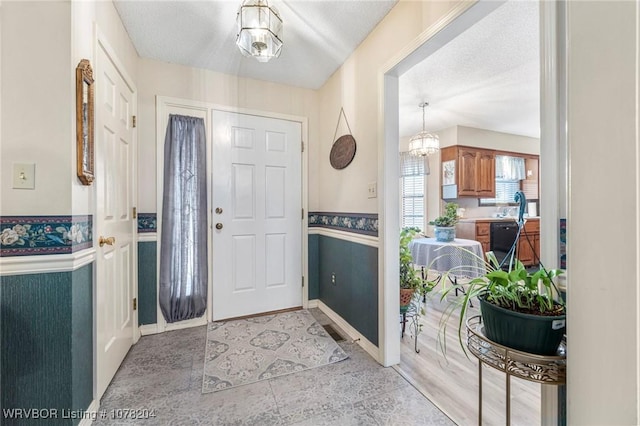 entrance foyer with a textured ceiling, an inviting chandelier, and sink