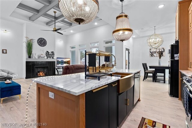 2205 Moody Rd, Barling, AR 72923 - kitchen featuring open floor plan, beamed ceiling, a kitchen island with sink, freestanding refrigerator, and a lit fireplace