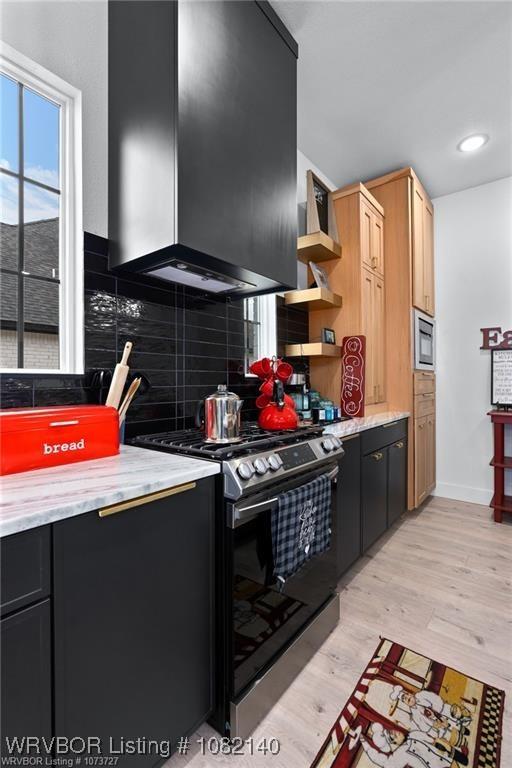 2205 Moody Rd, Barling, AR 72923 - kitchen with stainless steel range with gas cooktop, wall chimney range hood, open shelves, tasteful backsplash, and light wood-style flooring