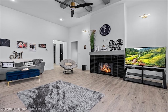 2205 Moody Rd, Barling, AR 72923 - living room with a high ceiling, wood finished floors, a ceiling fan, beamed ceiling, and a tiled fireplace