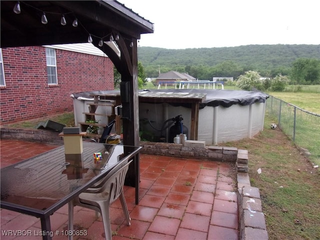view of patio / terrace featuring a fenced backyard, a covered pool, and a view of trees
