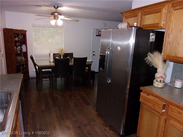kitchen featuring a ceiling fan, dark wood-style flooring, stainless steel fridge with ice dispenser, brown cabinets, and dark countertops