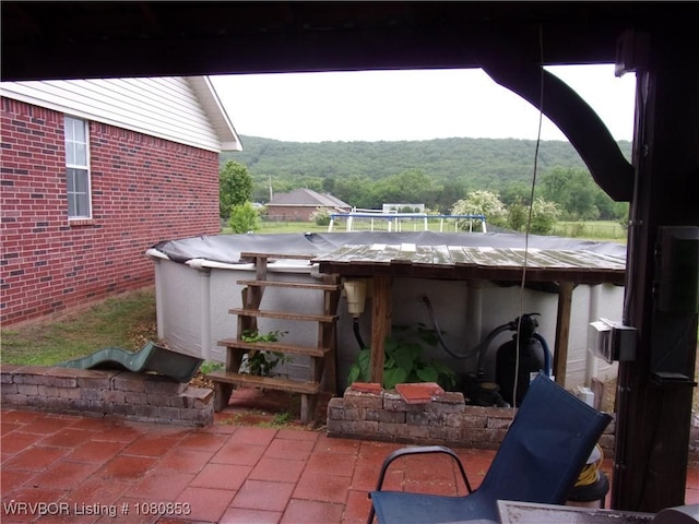 view of patio / terrace with a covered pool and a view of trees