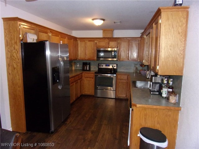 kitchen with a sink, brown cabinetry, visible vents, appliances with stainless steel finishes, and dark wood-style floors