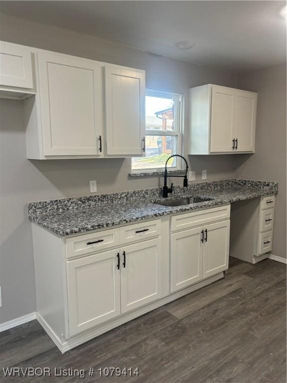 kitchen featuring dark stone countertops, a sink, and white cabinets