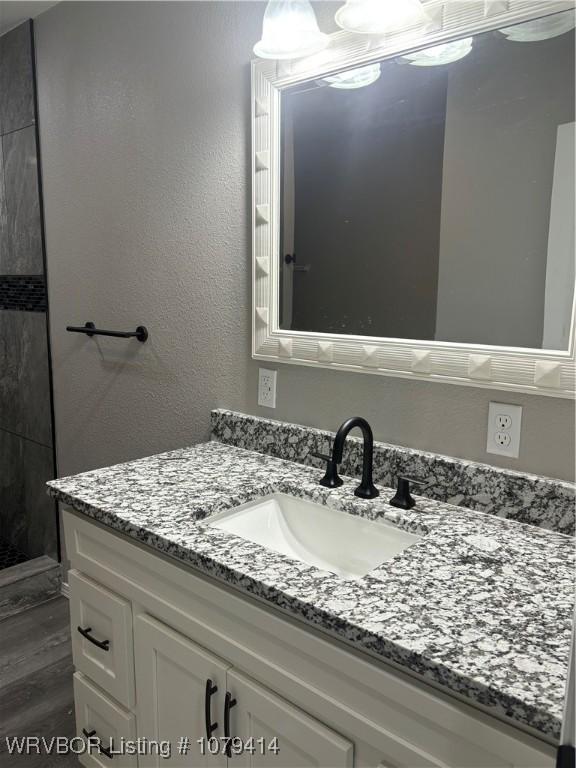 bathroom featuring a textured wall, vanity, and wood finished floors