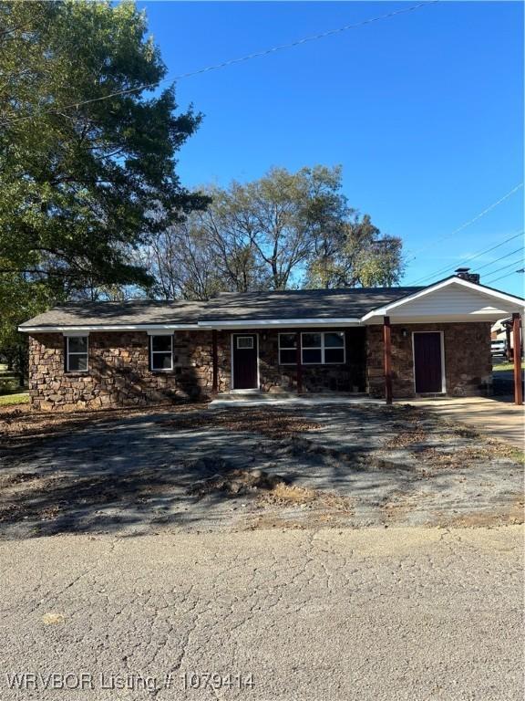 single story home with a carport, stone siding, and driveway