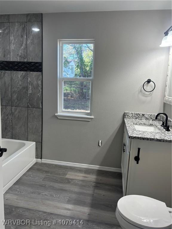 bathroom featuring toilet, wood finished floors, vanity, and baseboards