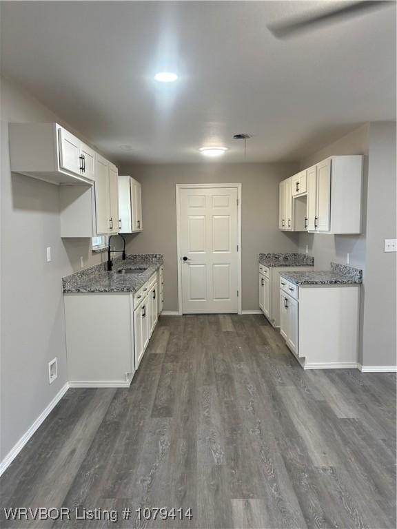 kitchen with stone counters, dark wood finished floors, white cabinets, and a sink