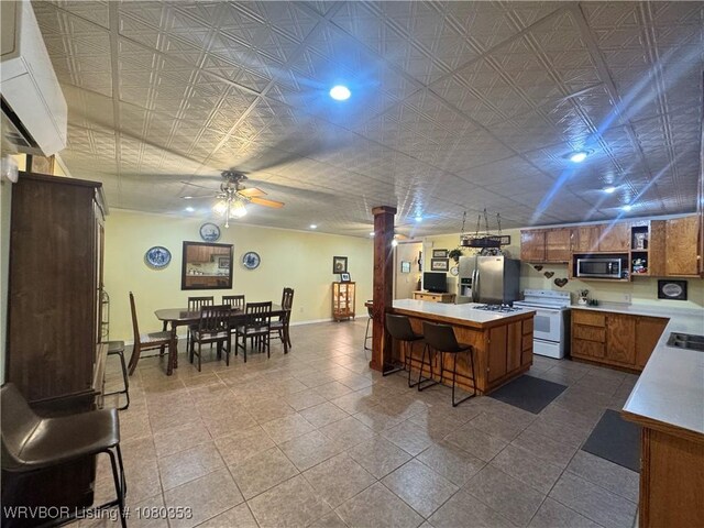 6538 110th Rd, Red Oak, OK 74563 - kitchen with brown cabinets, a breakfast bar, ceiling fan, baseboards, and appliances with stainless steel finishes