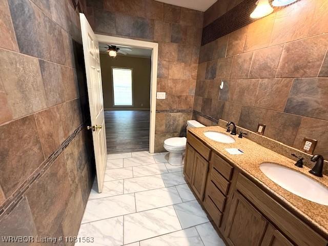 1434 W College St, Ozark, AR 72949 - bathroom with tile walls, toilet, double vanity, marble finish flooring, and ceiling fan