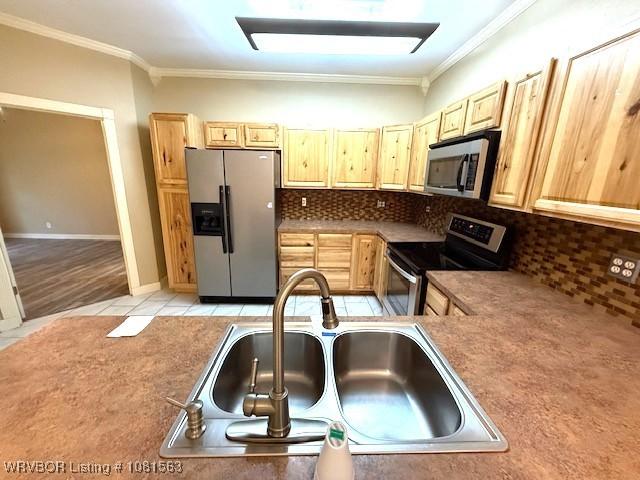 1434 W College St, Ozark, AR 72949 - kitchen featuring appliances with stainless steel finishes, a sink, ornamental molding, backsplash, and light tile patterned flooring